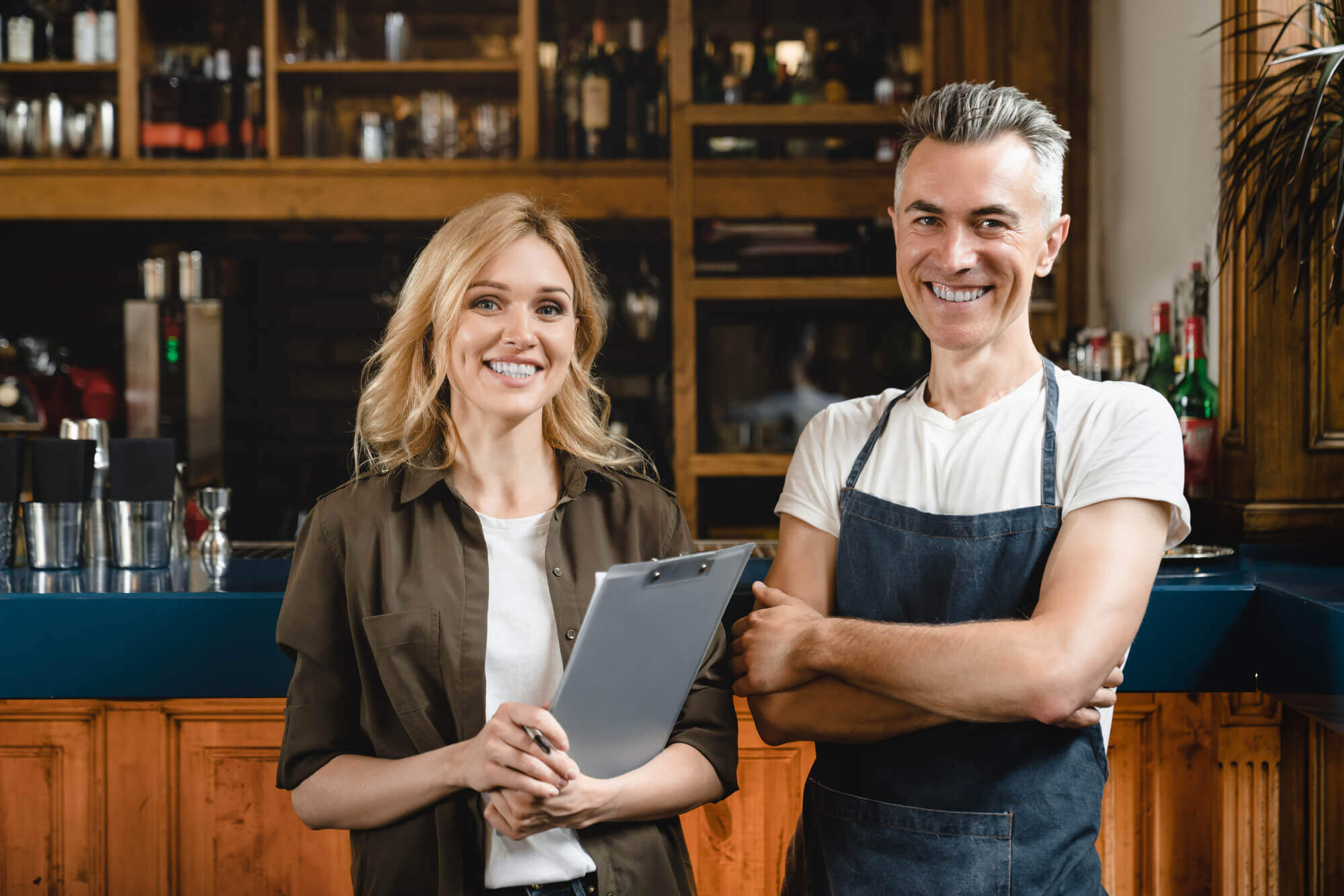 Smiling caucasian small business owner waiter barista with female auditor holding clipboard