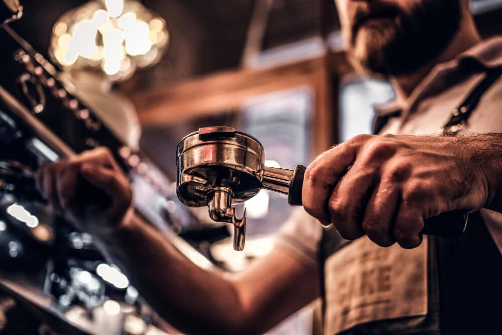 low-angle-photo-barista-cleans-portafilter-before-preparing-cappuccino-coffee-shop-restaurant-close-up